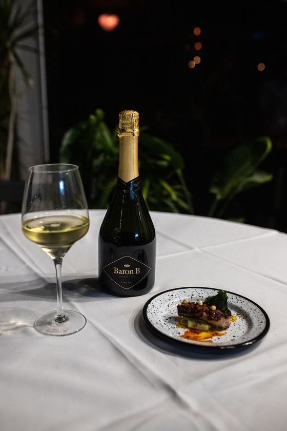 Botella de Baron B Cuvée Spéciale Extra Brut con copa y plato de maridaje