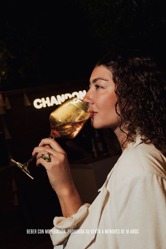 Invitada bebiendo Chandon frente al letrero iluminado de la marca
