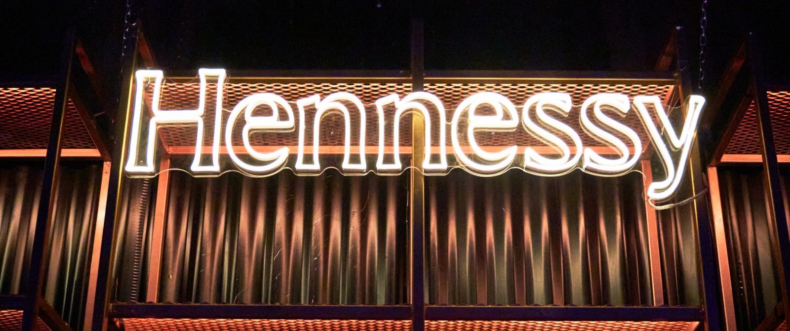 Letrero de neón de Hennessy sobre la barra con botellas iluminadas